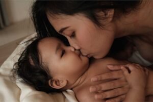 Close-up of mom kissing baby during a tender mom and baby photoshoot.