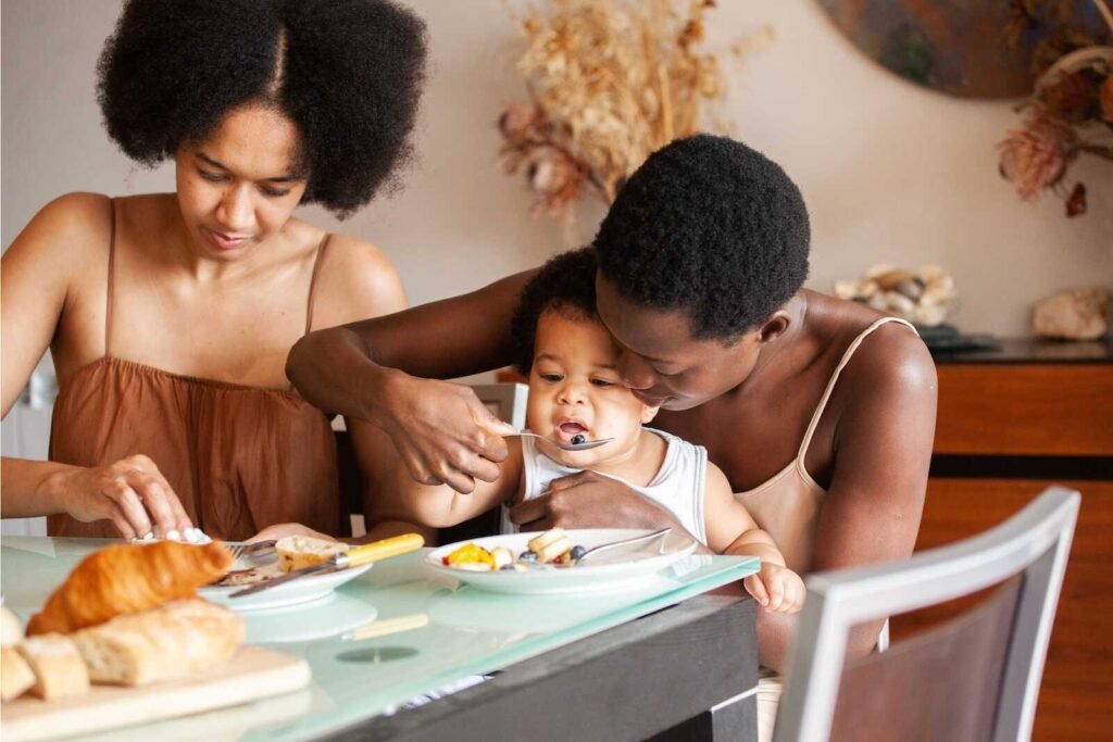 Parents feeding baby at table during a candid parents and baby photoshoot.