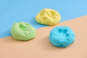 Blue, green, and yellow cloud dough with handprint impressions for sensory play