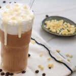 Iced white chocolate mocha with whipped cream and white chocolate drizzle on glass