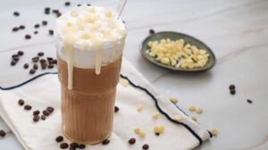 Iced white chocolate mocha with whipped cream and white chocolate drizzle on glass